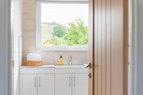 uma casa de banho com um lavatório e uma janela em Luxurious & Modern Large 5 Bed House, HotTub, Views! em Maidstone