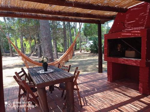 a wooden deck with a hammock and a table and chairs at Casa En Punta Ballena Zona Chihuahua Mínimo tres noches in Punta del Este
