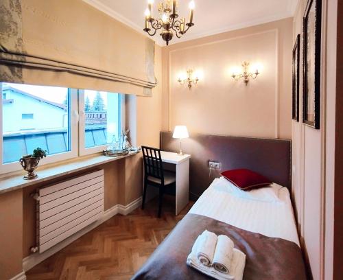 a bedroom with a bed and a desk and a window at Willa Krakowska in Raszyn
