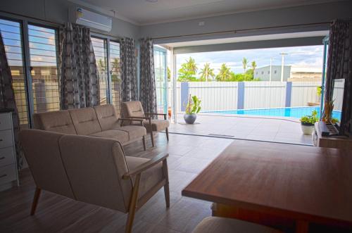 uma sala de estar com um sofá e uma piscina em Joe's Shack - A cosy oasis in Nadi close to the beach, supermarkets, restaurants, Denarau Island and the Marina. em Nadi