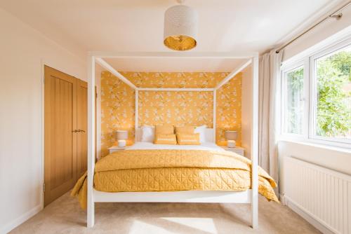 1 dormitorio con cama blanca y colcha amarilla en Luxurious & Modern Large 5 Bed House, HotTub, Views! en Maidstone