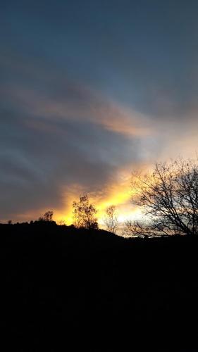 a sunset over a hill with trees in the foreground at Poggio La Grognola in Cannara