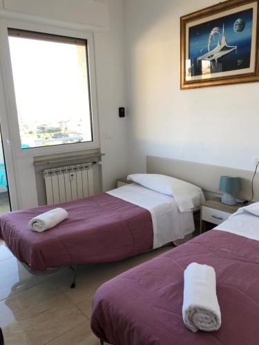 2 letti in una camera con finestra di Attico Tacito a Ventimiglia