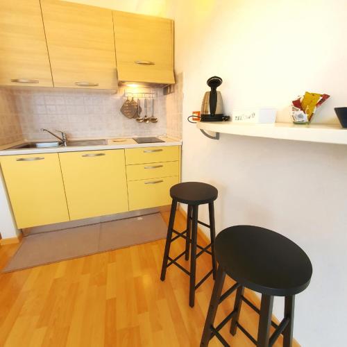 a kitchen with two stools and a counter with yellow cabinets at Il Portico Rosa in Cuglieri