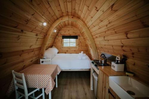 1 dormitorio en una cabaña de madera con 1 cama y lavamanos en Oak SPECIAL WINTER OFFERS - Hot tub & Log burner en Barmouth