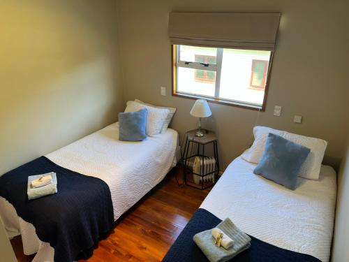 a bedroom with two beds with blue pillows at Coastal Lodge Kekerengu in Kekerengu