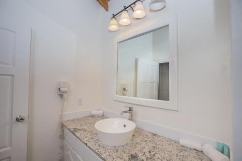 a white bathroom with a sink and a mirror at Casa de Suenos Home in Sandy Bay