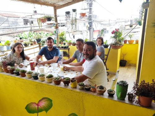 un grupo de personas sentadas en una mesa con plantas en Porto Hostel, en Porto Seguro