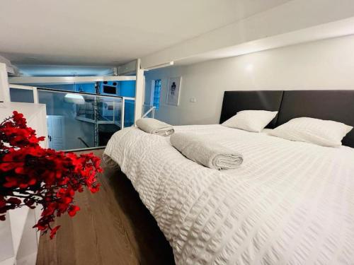 1 dormitorio con 1 cama grande con sábanas blancas y flores rojas en Unique loft apartment Located 15 minutes from the Champs Élysées, en Saint-Ouen