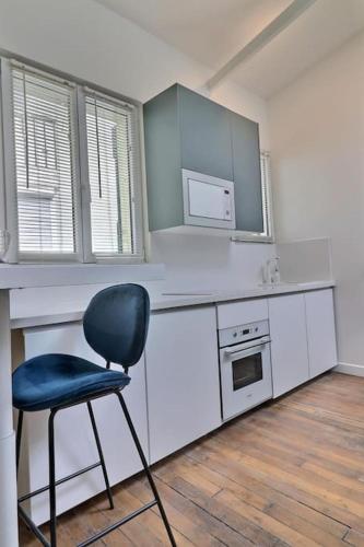 une cuisine avec une chaise bleue dans une pièce dans l'établissement Unique loft apartment Located 15 minutes from the Champs Élysées, à Saint-Ouen