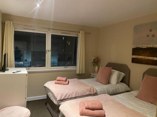 City Centre 2 bedroom apartment, secure parking. في غلاسكو: غرفة نوم بسريرين عليها مناشف وردية