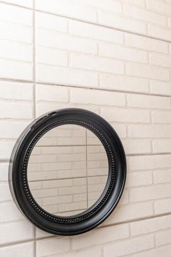 a black circular mirror hanging on a brick wall at Nkosazana Guest House in Durban