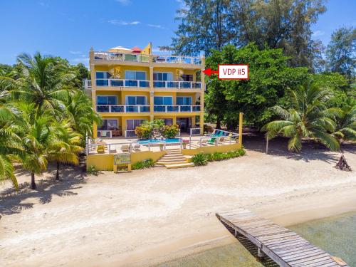 a large yellow building on a beach with palm trees at Del Playa Penthouse #5 Condo in West End