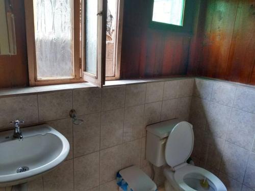 a bathroom with a toilet and a sink and a window at Casa en el rincon familiar en Mindo in Mindo