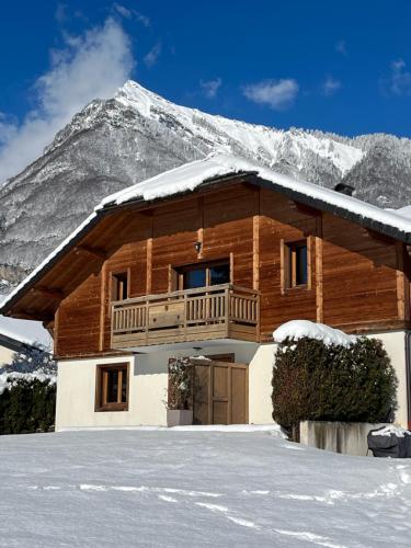 a log cabin with a snow covered mountain in the background at Gîte Balnéo Au Coeur des Alpes in Taninges