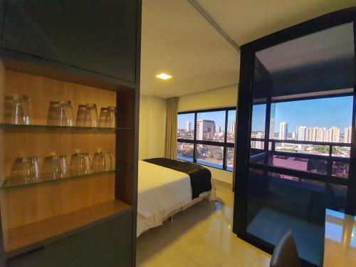 a room with a bed and a window with a view at Estúdio Confortável no 12º Andar do Ed. Vertigo in Campo Grande