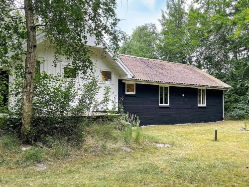 a small black and white house in a yard at 6 person holiday home in Hadsund in Odde