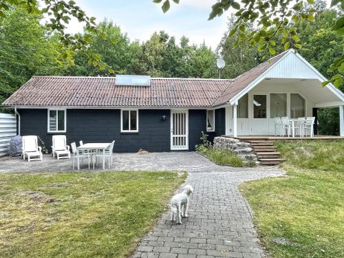 Oddeにある6 person holiday home in Hadsundの青い家の前に立つ犬