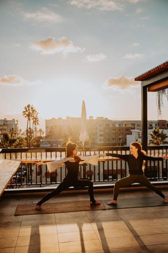 two women performing a yoga pose on a rooftop at The Brick Boutique Hotel in Oceanside