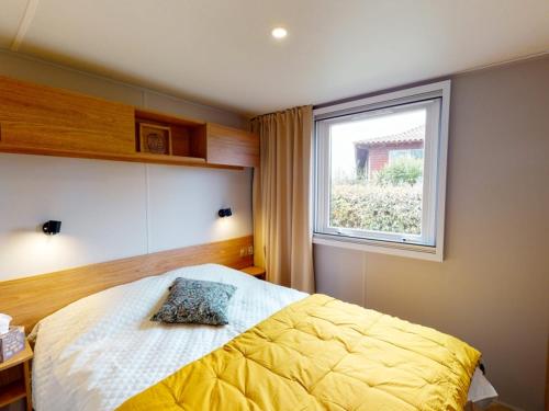 a bedroom with a yellow bed with a window at Mobilhome NEUF Mar estang Accès Plage in Canet-en-Roussillon