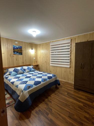 a bedroom with a bed with a blue and white blanket at Cabañas Rukafun 2 in Pucón