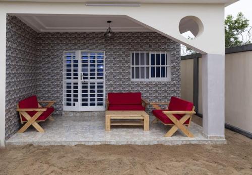 two red chairs and a table on a patio at Maison Bethel Kpogan Afidenigba in Azyagbang