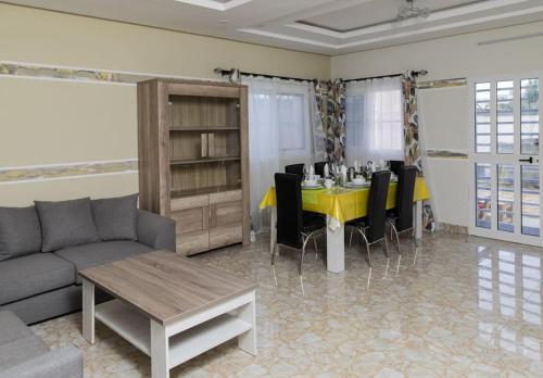 ein Wohnzimmer mit einem gelben Tisch und schwarzen Stühlen in der Unterkunft Maison Bethel Kpogan Afidenigba 