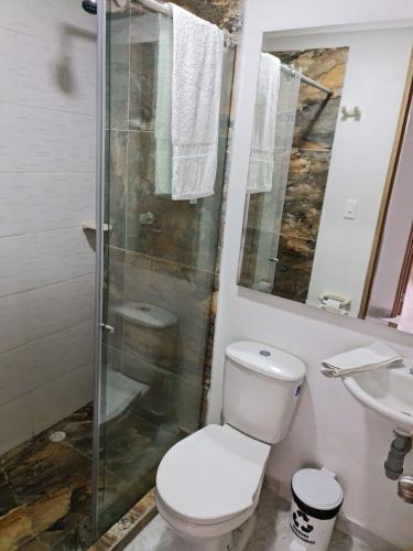 a bathroom with a toilet and a glass shower at Apartamento Completo Parqueadero - Ibagué - cerezo in Ibagué