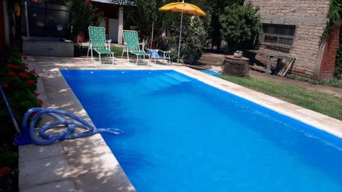una piscina azul con sillas y sombrilla en Complejo Los Platanos en General Alvear