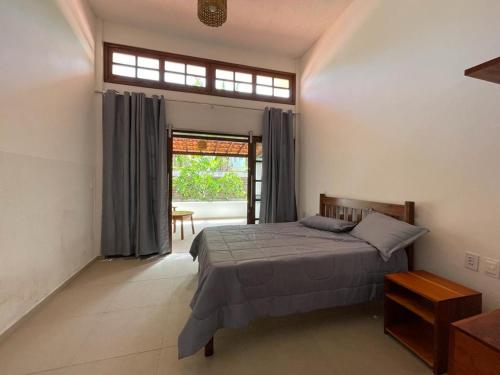 een slaapkamer met een bed en een groot raam bij Canoa Azul in Garapuá