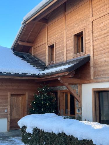 a building with snow on the roof and a christmas tree at Gîte Balnéo Au Coeur des Alpes in Taninges