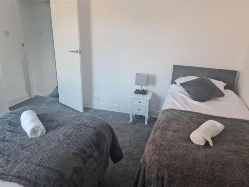 two beds in a bedroom with towels on them at Primrose Stays - 3 bedroom House in Stoke on Trent