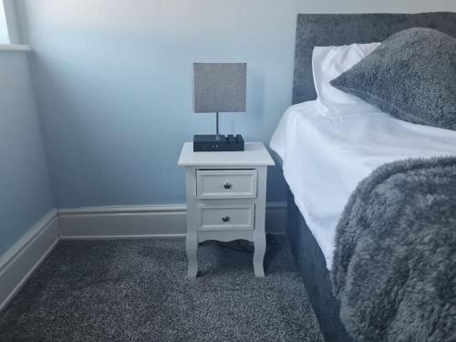 a bed with a night stand with a lamp on it at Primrose Stays - 3 bedroom House in Stoke on Trent