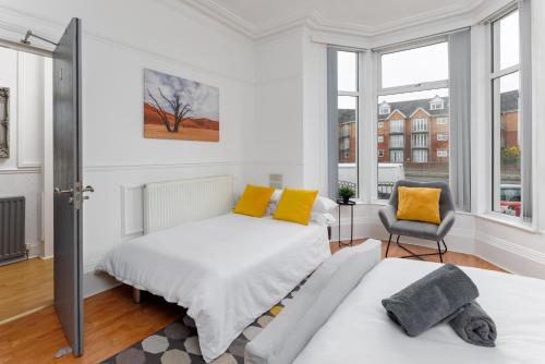 um quarto branco com uma cama e uma cadeira em FLATZY - 6 bed Oasis Close to Football Stadiums em Liverpool