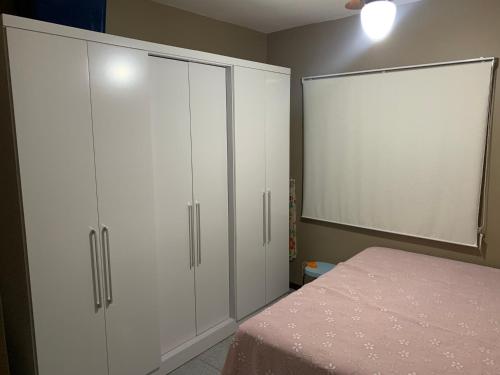 1 dormitorio con 2 armarios blancos y 1 cama en Apartamento em Cabo Frio, en Cabo Frío