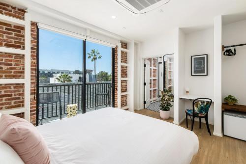 a bedroom with a white bed and a balcony at The Brick Boutique Hotel in Oceanside