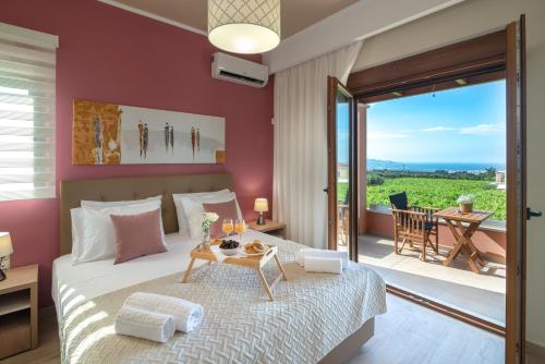a bedroom with a bed with a table and a balcony at Cretan Vineyard Hill Villa 2 in Áno Kalésia