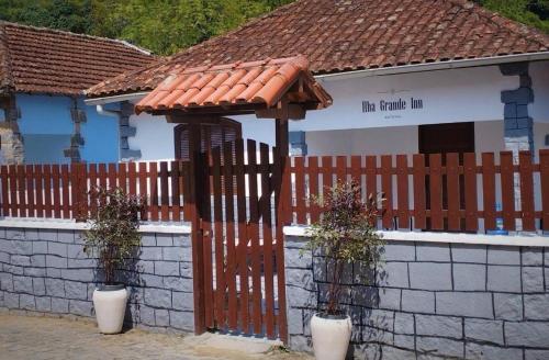 a house with a wooden fence and a building at Ilha Grande Inn in Abraão