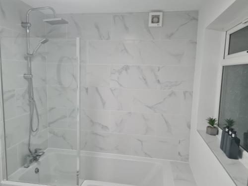 uma casa de banho branca com um chuveiro com uma porta de vidro em Primrose Stays - 3 bedroom House em Stoke-on-Trent