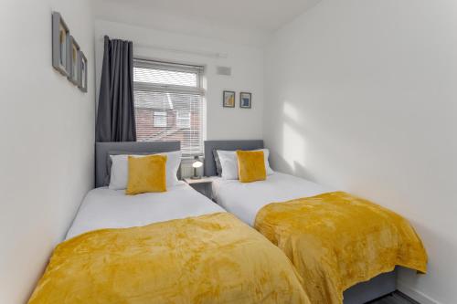 two beds in a room with yellow sheets at The Empress 2 Bed Terraced House in Liverpool
