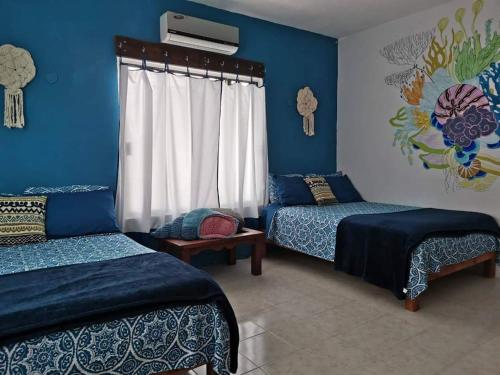 Un dormitorio con dos camas y una pared azul. en Casa Chen-Huaye, en Isla Mujeres