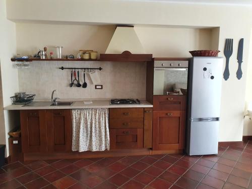 cocina con armarios de madera y nevera blanca en Casa La Ferula apt1 vicino al mare e Taormina, en SantʼAlessio Siculo