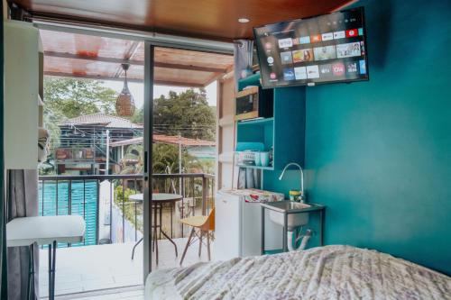 a room with a bed and a balcony with a television at Wanderlust in Jacó