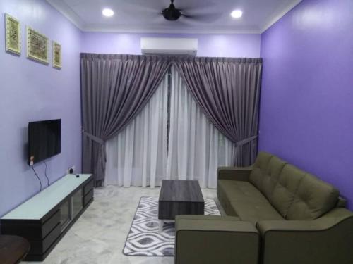 a living room with a couch and a tv at ISMAYUS GUESTHOUSE in Kampong Chinchang