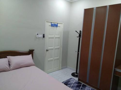 a bedroom with a white bed and a door with at ISMAYUS GUESTHOUSE in Kampong Chinchang