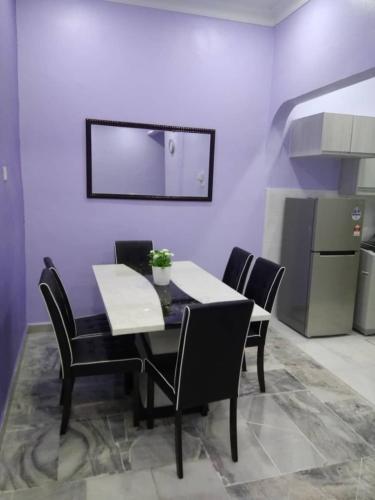 a dining room table with black chairs and a kitchen at ISMAYUS GUESTHOUSE in Kampong Chinchang