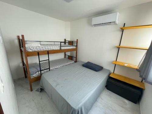 um pequeno quarto com uma cama e 2 beliches em Flats do Lucca em Tamandaré