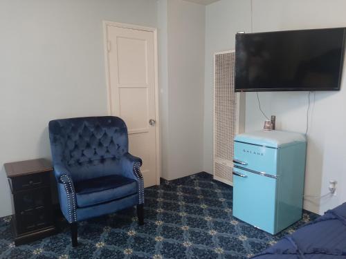 a room with a blue chair and a television at THE NEW STAR MOTEL - 1950s Extended-Stay Lodging and Retreat Center in Moreno Valley