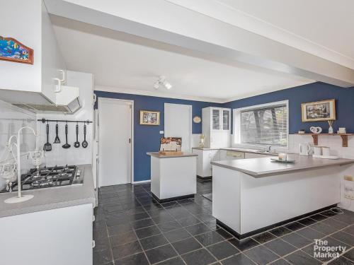 cocina grande con paredes azules y electrodomésticos blancos en Mannering Lake House, en Mannering Park