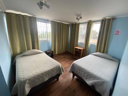 a bedroom with two beds and two windows at Casa cercana a playa Los Vilos in Los Vilos